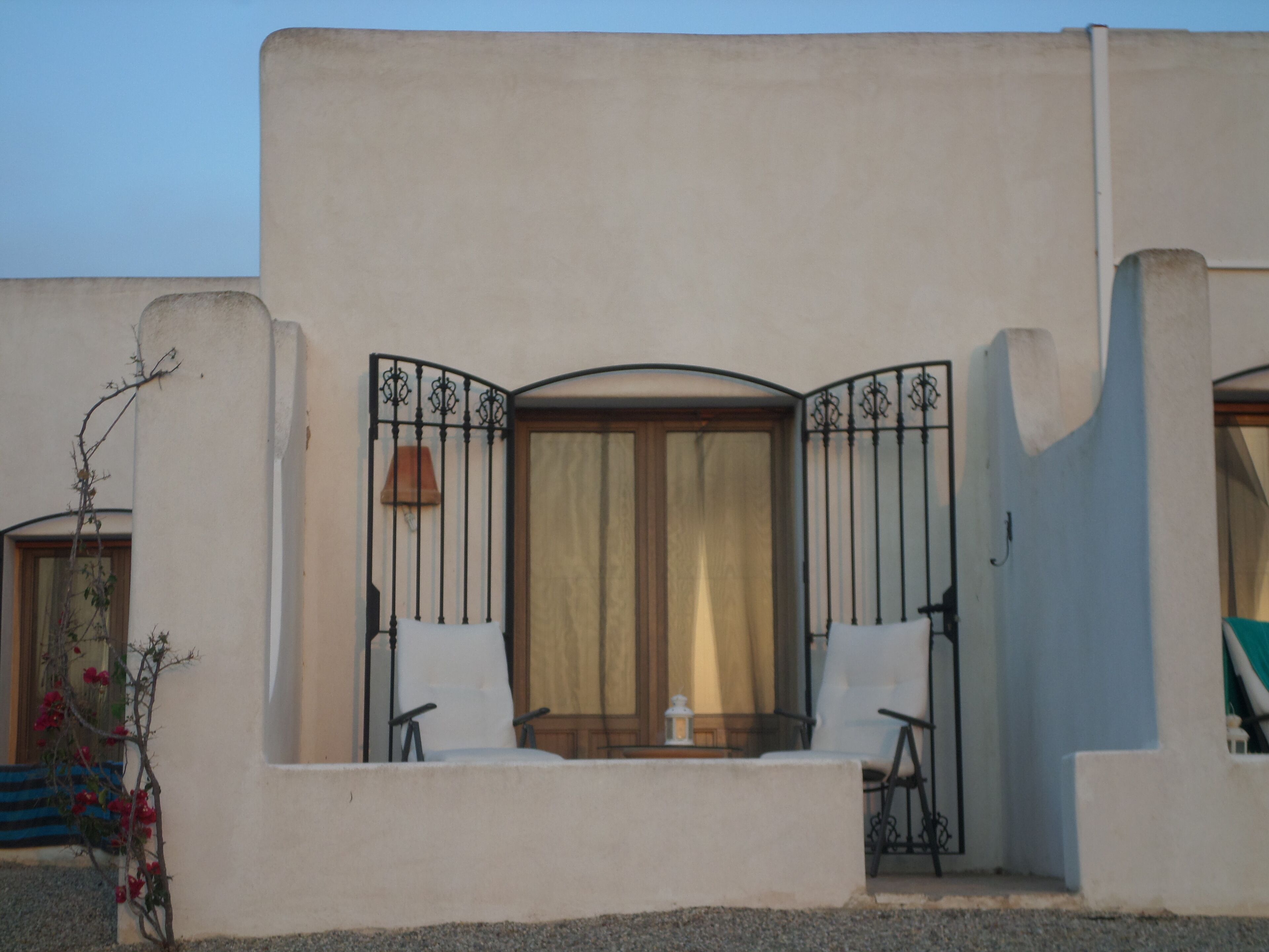 A building with a balcony, a window with curtains, and a door.
