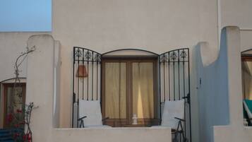 A building with a balcony, a window with curtains, and a door.