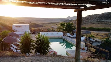 Una piscina al aire libre, sombrillas, sillones reclinables de piscina