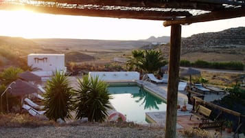 Una piscina al aire libre, sombrillas, tumbonas