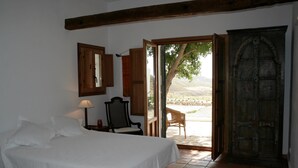 Une chambre à coucher avec un lit, une chaise, une porte en bois et une vue sur l’extérieur.