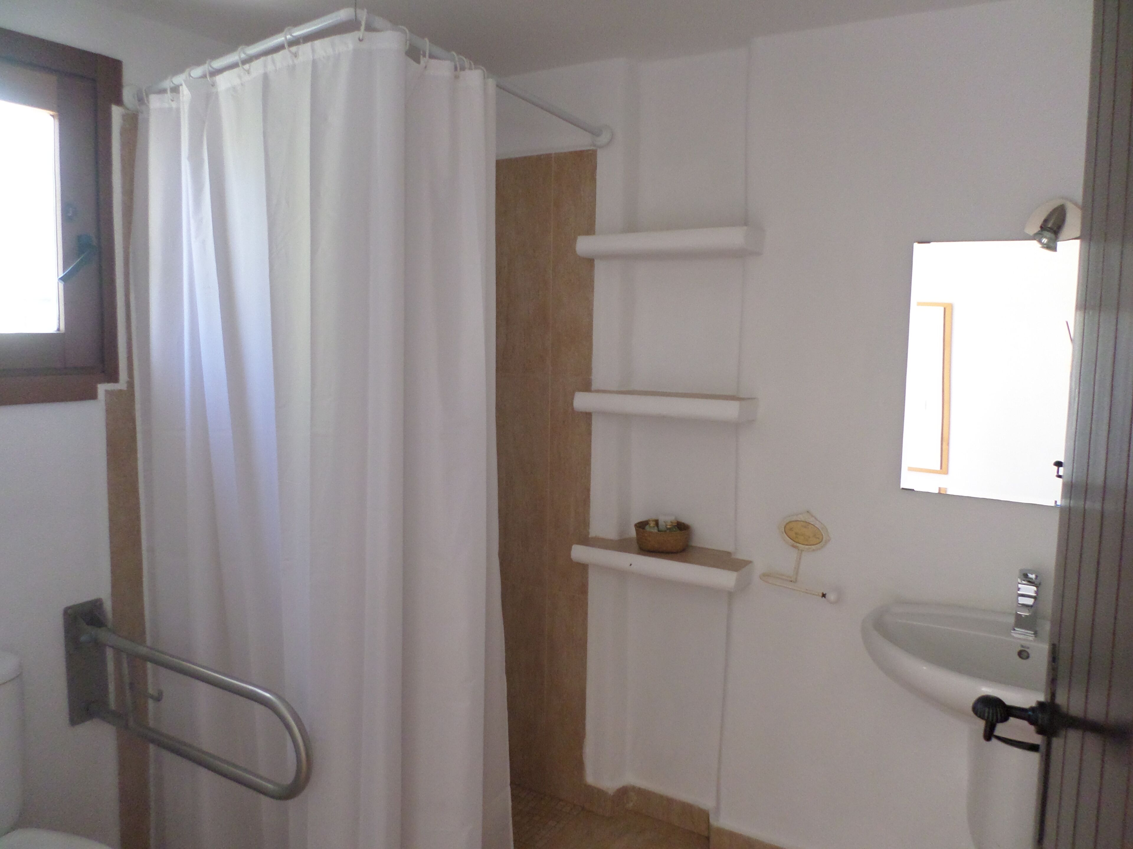 A bathroom with a shower curtain, a toilet, a sink, and a mirror.