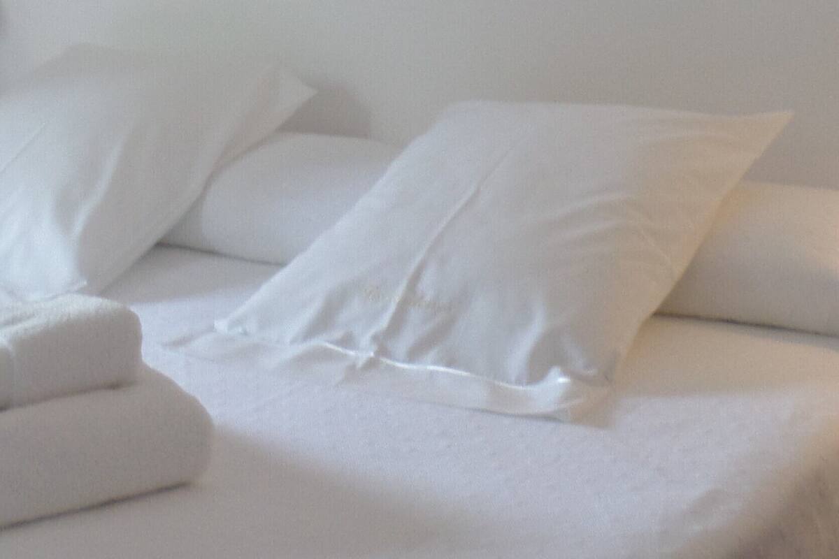 A bed with white bedding and pillows.