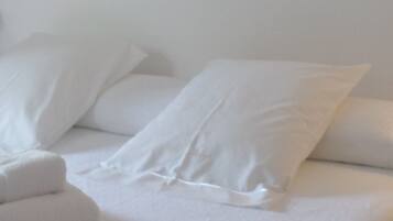 Een bed met witte lakens en kussens.