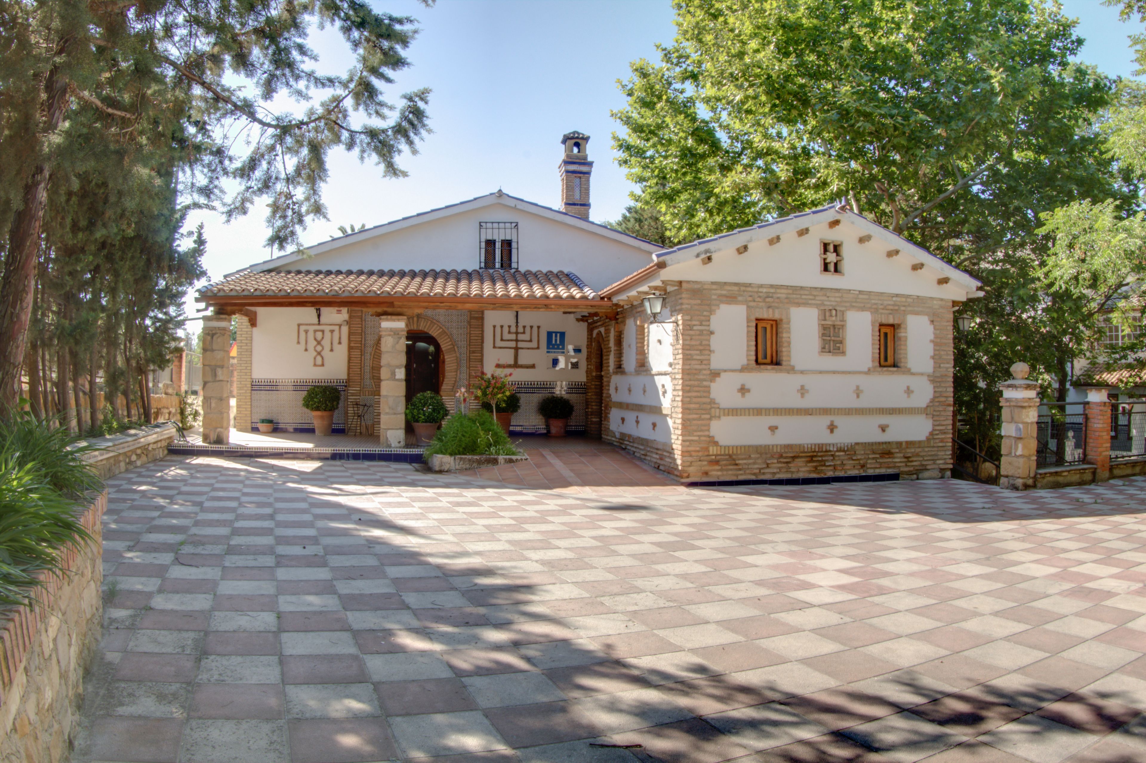 A two-story building with a tiled roof, a small tower, and a covered entrance.