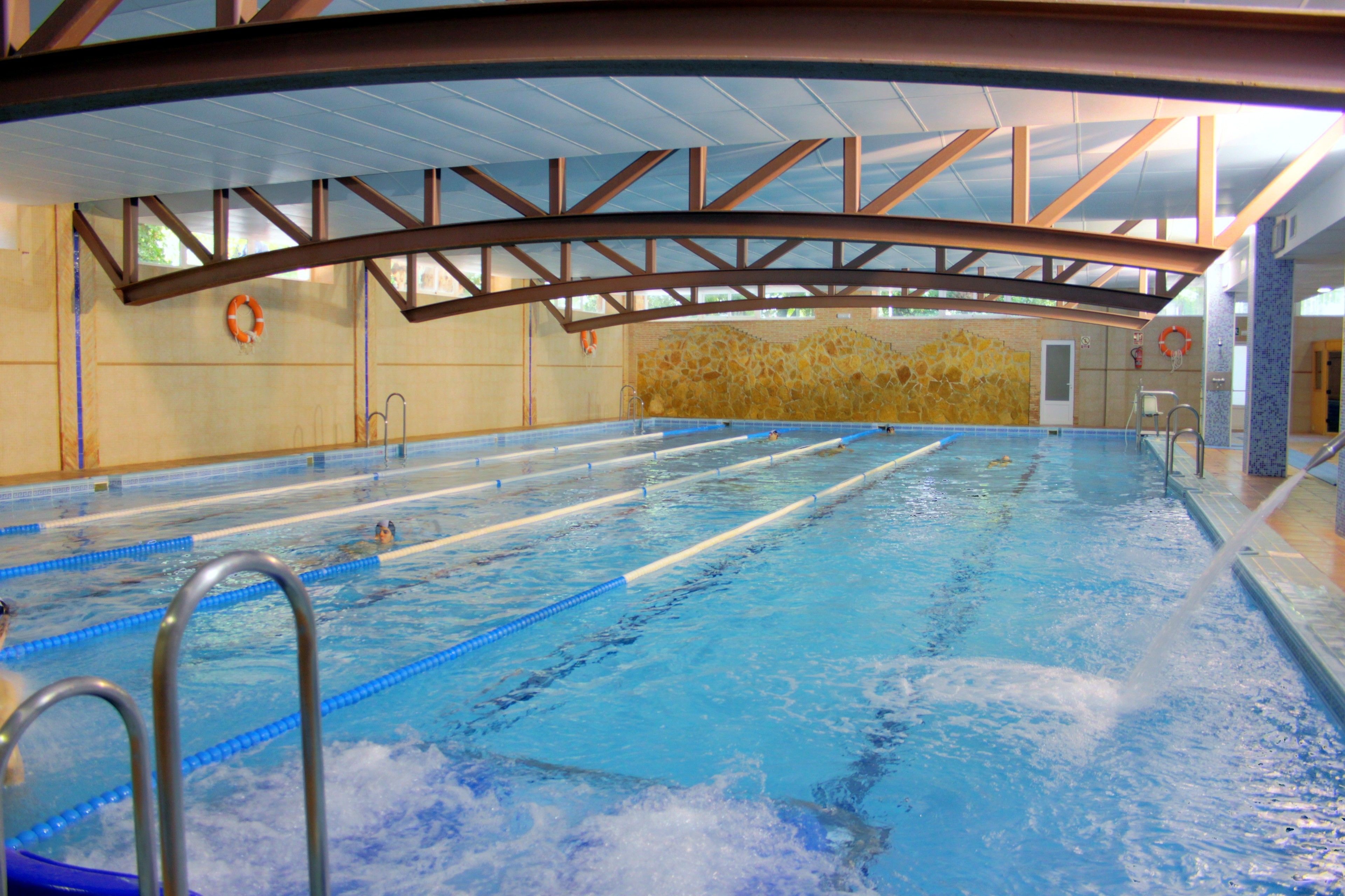 Piscina interior con carriles bien definidos, sillas de salvavidas y una pared de piedra.