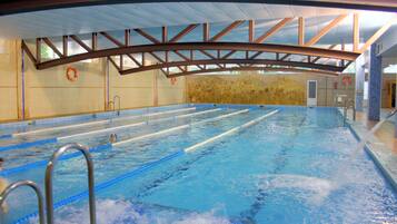 Piscina interior con carriles bien definidos, sillas de salvavidas y una pared de piedra.