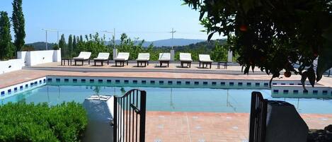 A pool area with lounge chairs and a view of the landscape.