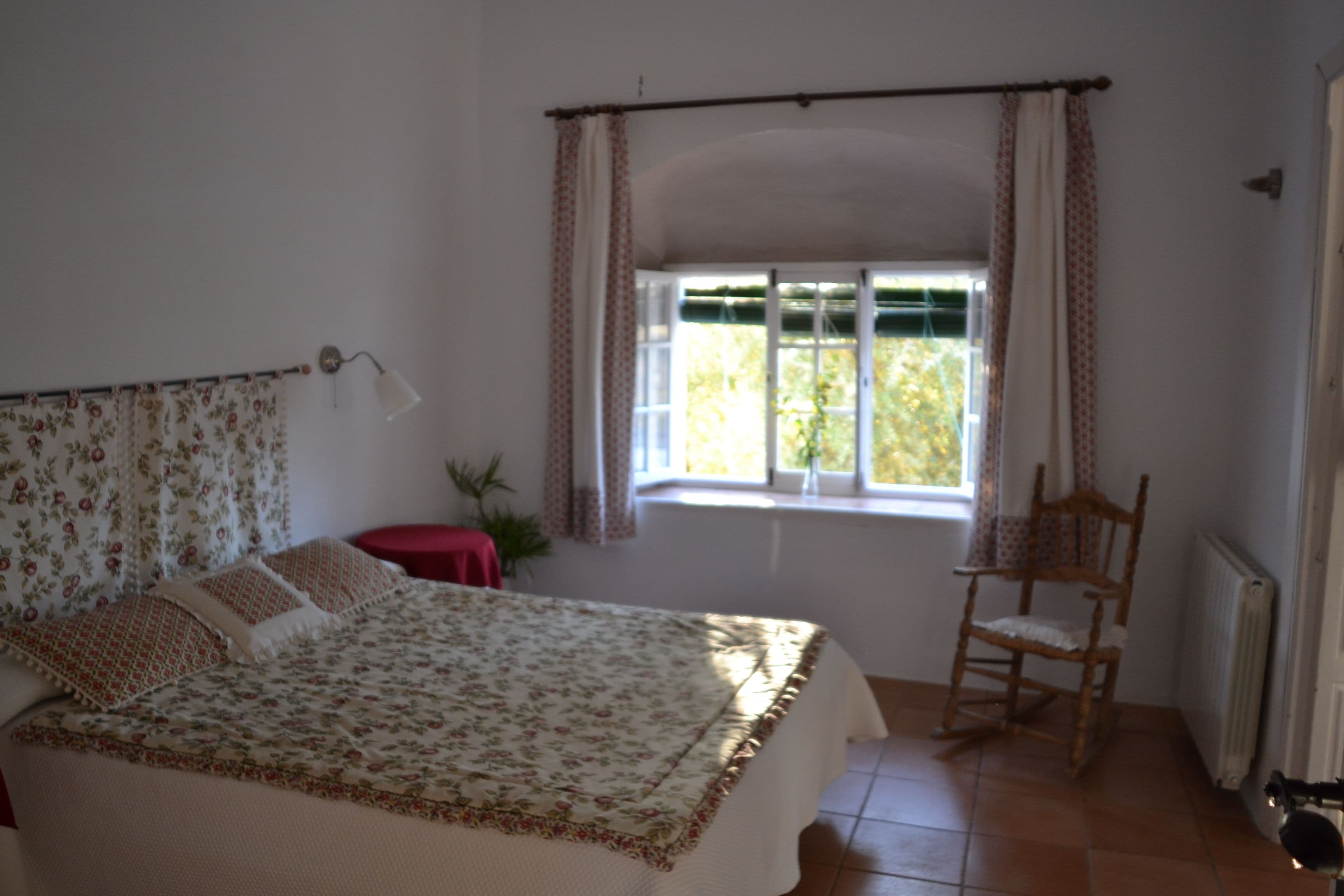 A bedroom with a bed, a chair, a window, and a radiator.