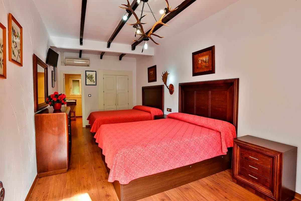 Un dormitorio con dos camas, muebles de madera, una lámpara en el techo y adornos en la pared.