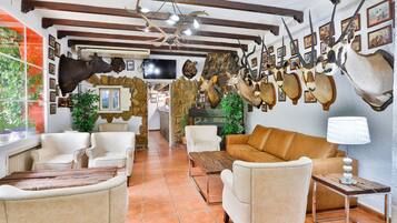 Una habitación con chimenea, sofás de cuero y cabezas de animales montadas en la pared.