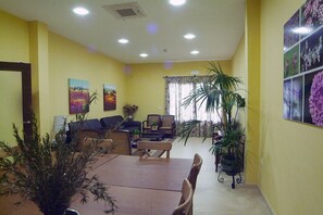 A living room with a dining table, sofas, and potted plants. - Sancho IV Apartamentos Turísticos Rurales (Cortegana)