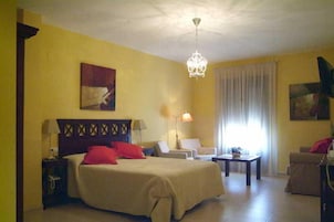 Una habitación de hotel con una cama, dos sillas, una mesita y una lámpara.