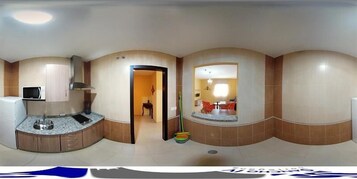 Vista panorámica de una habitación de hotel con cocina, comedor y baño.