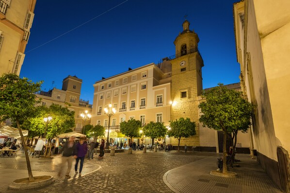 Una plaza adoquinada con edificios históricos, una torre del reloj y zonas de estar al aire libre.
