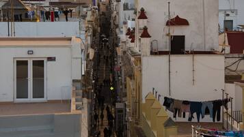 A narrow urban street with buildings on both sides, a visible staircase, and hanging laundry.