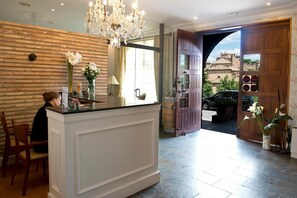 A reception area with a wooden wall, a chandelier, and a large wooden door leading outside. - Hotel Santa María de Alquézar (Alquezar)