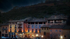 Un hotel de varios pisos, con entrada principal y mobiliario exterior.