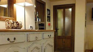 A spacious hallway with a cream-colored cabinet featuring ornate handles and a woven basket on top. A wooden door with frosted glass panels is visible in the background.