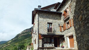 A stone building with a balcony, a wooden door, and a sign indicating a hotel.