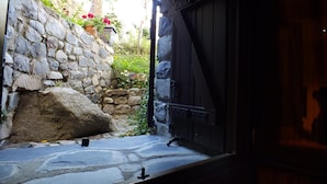 A stone wall with a large rock and a potted plant.
