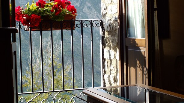 A balcony with a flower box, a wooden bench, and a view of mountains.