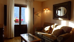 A living room with a sofa, a glass-top coffee table, a floor lamp, and a mirror on the wall.