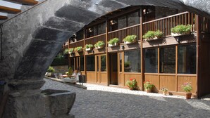 A stone building with wooden balconies and potted plants. - Hotel Casa Cornel (Benasque)