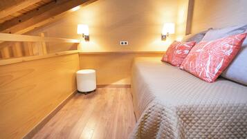 Un dormitorio acogedor con techo de madera, una cama con cubrecama acolchado y dos lámparas de pared.