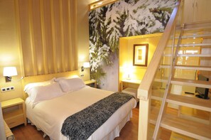 A hotel room with a bed, nightstands, a lamp, a painting, and a wooden staircase. - Hotel Casa Cornel (Benasque)