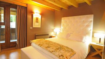 Un dormitorio con una cama grande, vigas de madera en el techo, un radiador y una ventana con cortinas.