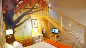 A hotel room with a bed, a desk with a lamp, a television, and a staircase. - Hotel Casa Cornel (Benasque)