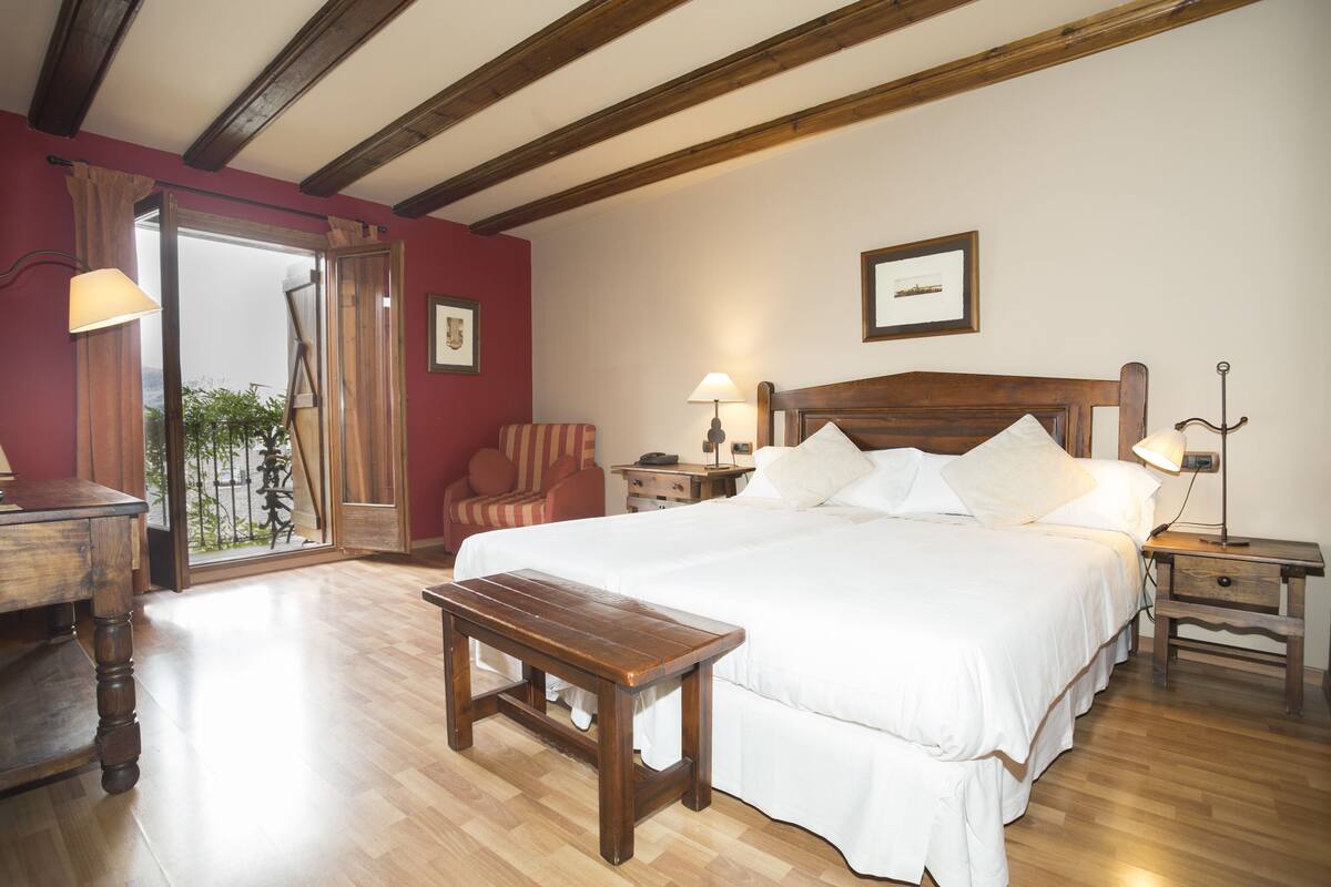 A bedroom with a large bed, wooden bench, and a chair.