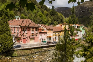 A riverside town with colorful buildings, a bridge, and a mountain in the background.