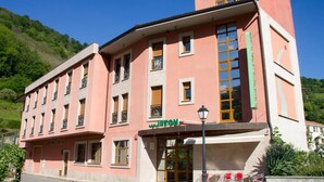Ein pinkfarbenes Gebäude mit einem Schild, auf dem „HOTEL“ steht, und einem grünen Schild über dem Eingang.