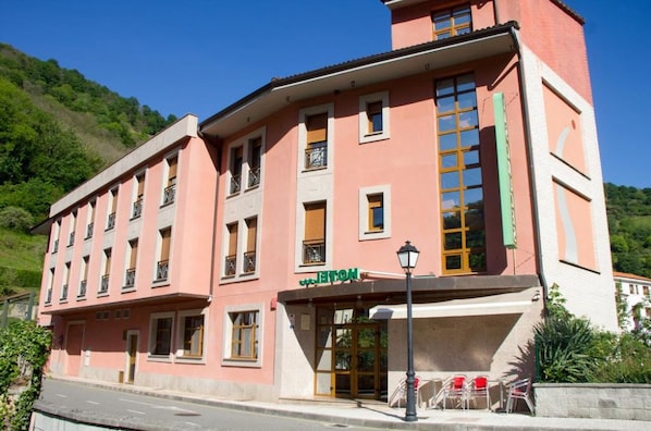 A pink building with a sign reading "HOTEL" and a green sign above the entrance.