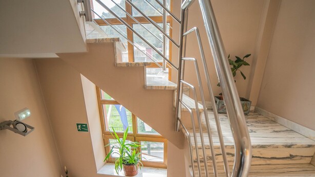 Eine Marmortreppe mit Metallgeländern, einem Blumentopf und einem kleinen Fenster mit Aussicht.