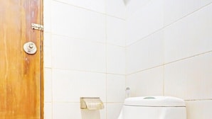 A toilet in a bathroom with white tiles and a wooden door. - Spot ON 89962 Perfect Class Hotel (Kuala Lumpur)