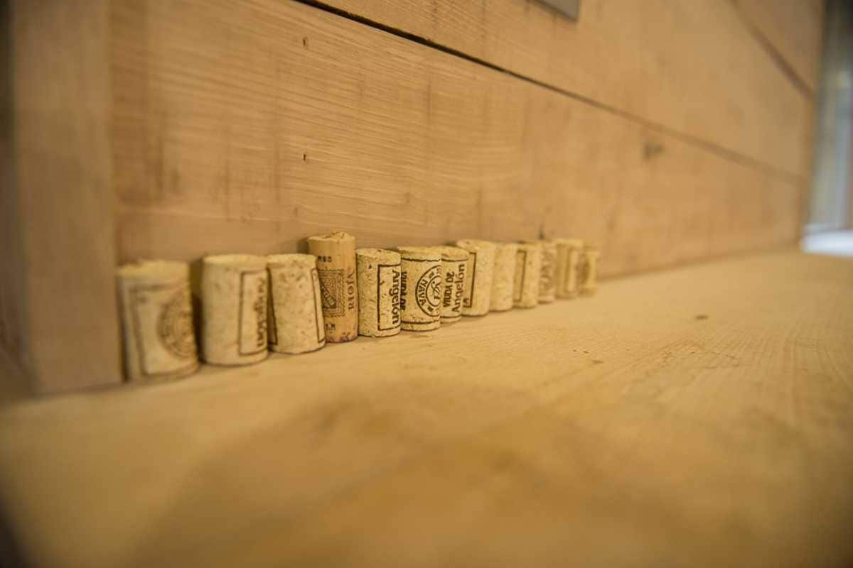 Une rangée de bouchons de bouteilles de vin vides est alignée contre un mur en bois.