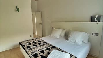 Un dormitorio con cama, techo de madera y pared blanca.