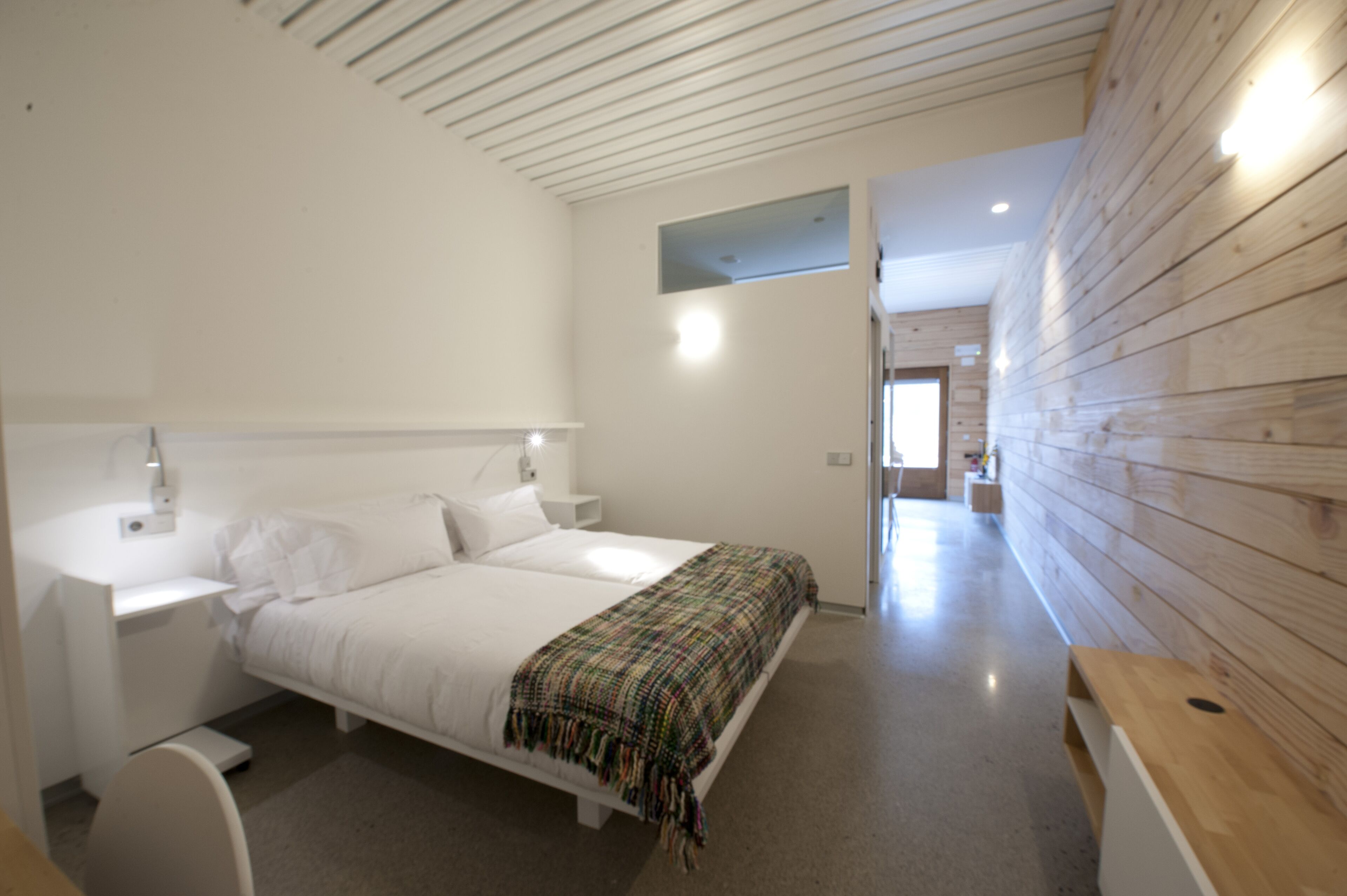 Ein Schlafzimmer mit einem Bett, Nachttischen, einem Beistelltisch und einer Holzwand.