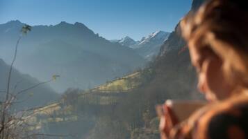 Una persona sosteniendo una taza, con un paisaje montañoso de fondo.