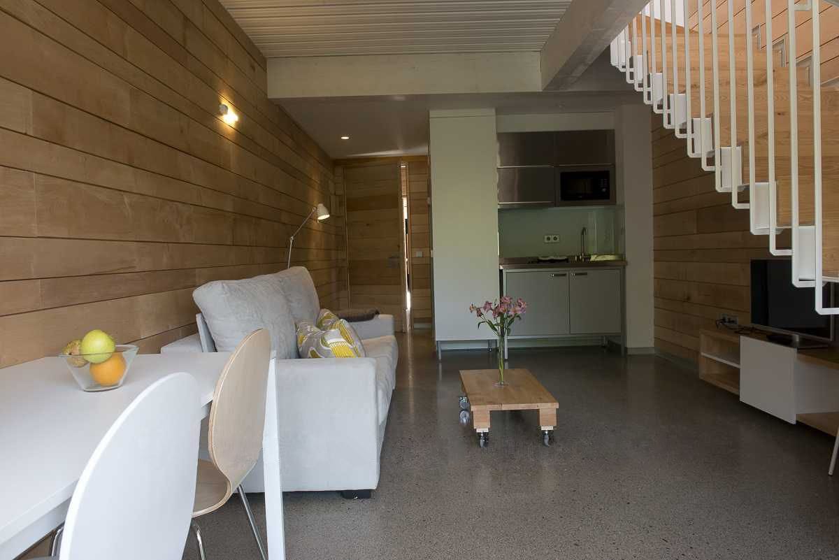 Una sala moderna con un sofá, una mesa de centro y una zona de comedor con una mesa y sillas.