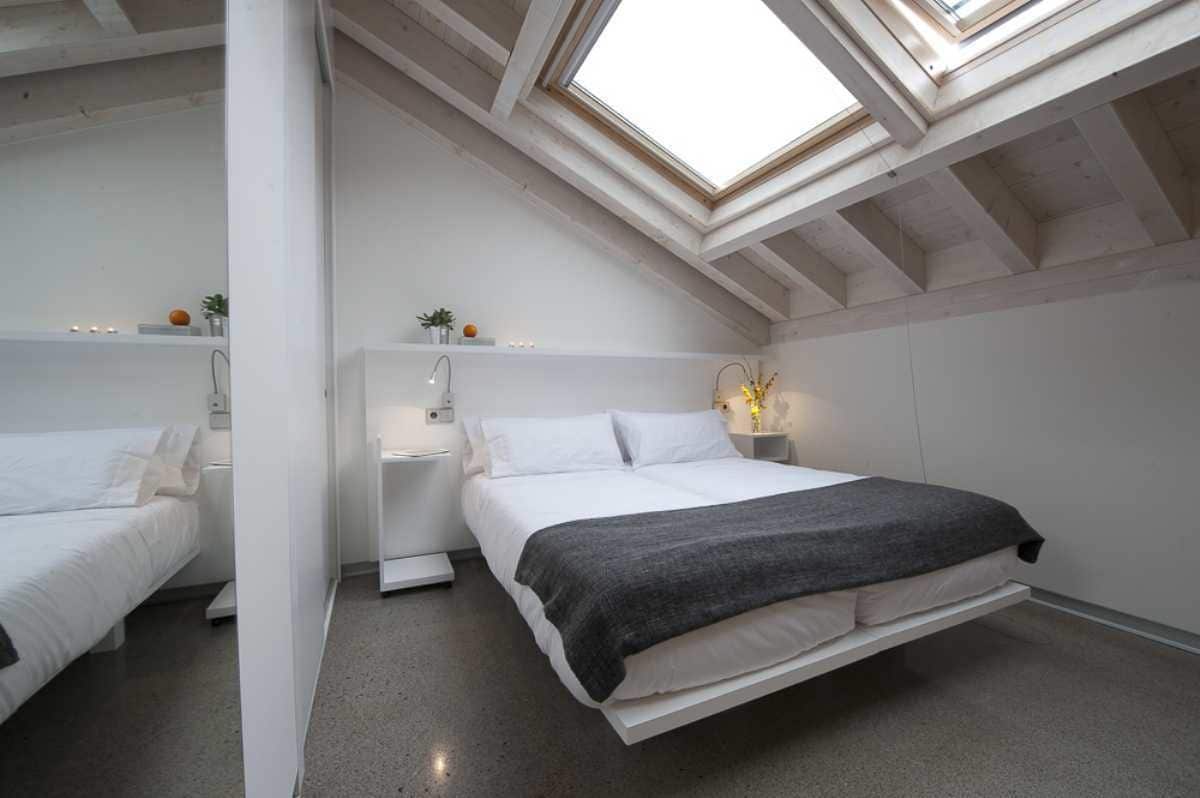 A modern bedroom with a skylight, a bed, bedside tables, and a nightstand.