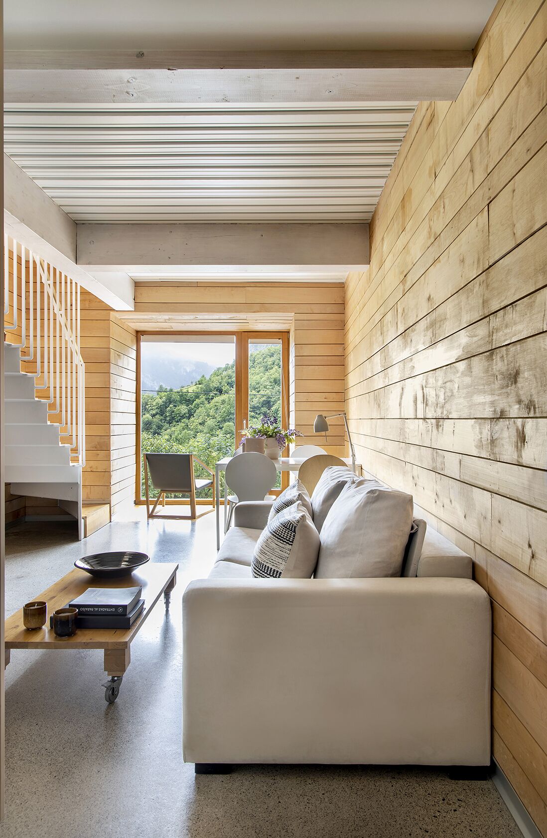 Un intérieur moderne avec un mur en bois, un canapé blanc, une table à manger et un escalier.
