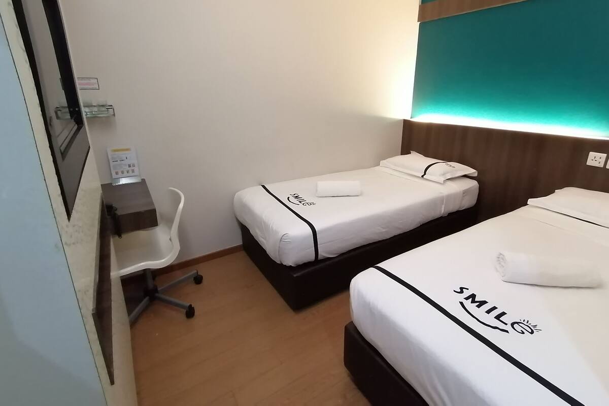 A hotel room with two beds, a desk, and a chair.