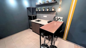 A compact kitchen with a sink, countertop, and a small dining area with stools. - Smile Hotel USJ (Subang Jaya)