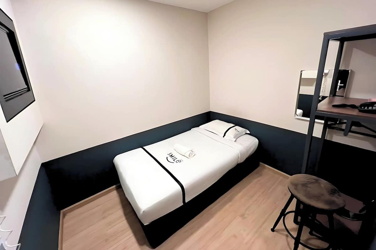 A compact room with a bed, a desk, and a chair.