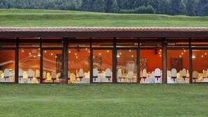 Un edificio con un amplio comedor, ventanas grandes y vistas a un campo verde.
