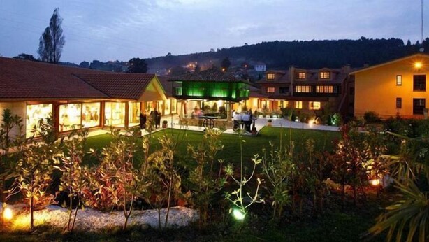 Un hotel con varias construcciones, un jardín bien cuidado y una piscina visible.